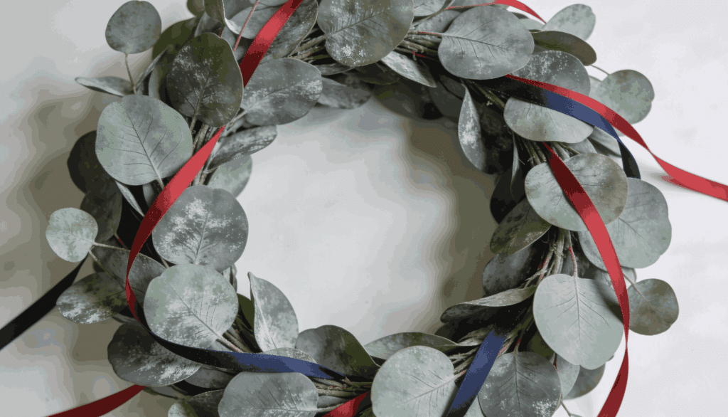 Modern eucalyptus wreath with red and navy ribbon accents.