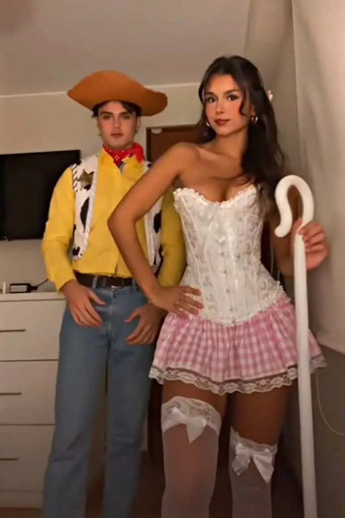 Woody and Little Bo Peep couples Halloween costume inspired by Toy Story, featuring Woody in a cowboy outfit and Bo Peep in a corset, pink gingham skirt, and shepherd&rsquo;s staff.